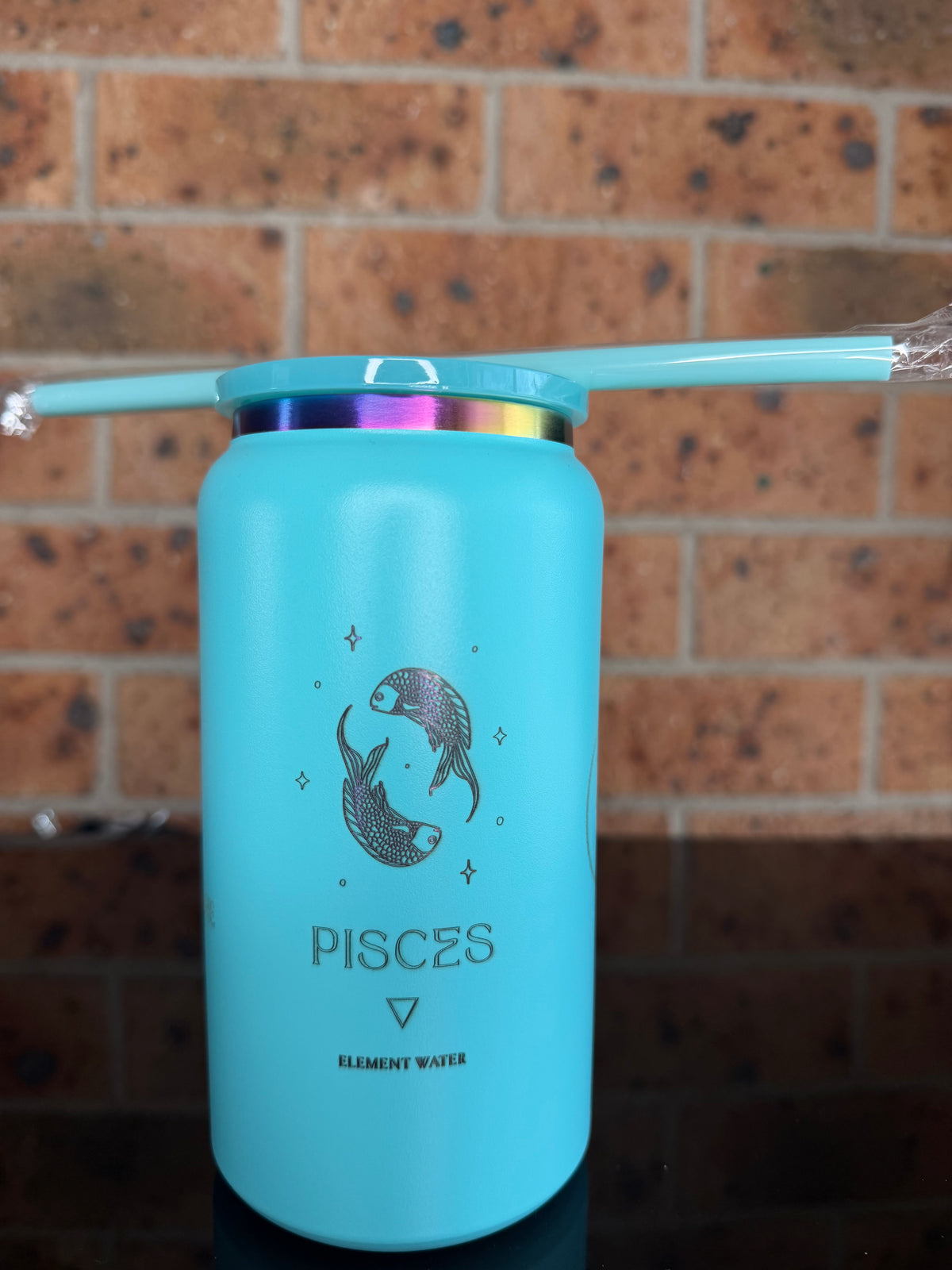 A light blue insulated water bottle with a matching straw, featuring a black Pisces zodiac symbol and text, resting on a brown tiled floor. Pisces tumbler, engraved Pisces gift, turquoise tumbler, astrology cup, personalized travel mug, zodiac gifts, insulated coffee tumbler.